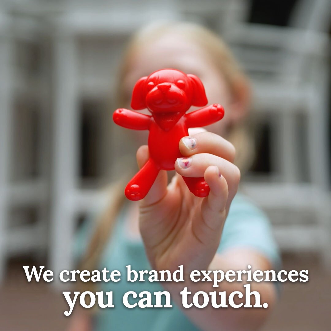 A grade school aged girl holds a red plastic toy puppy close to the camera. C3 creates brand experiences you can touch.