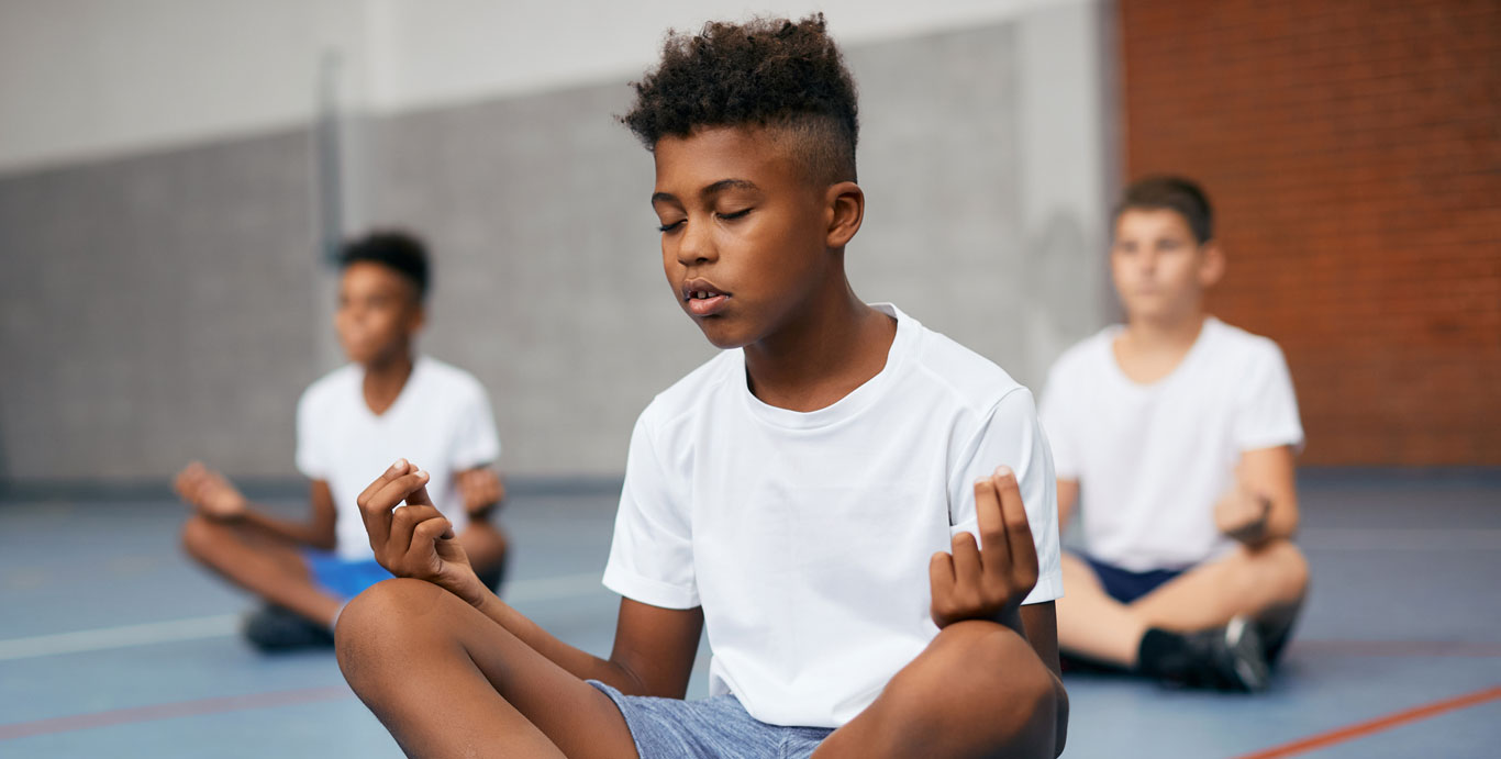 C3 Lab: Meet Gen Alpha – Grade school boys meditate in a school gymnasium.