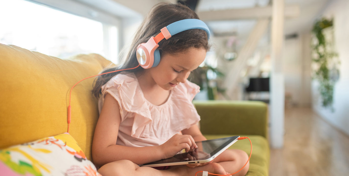 C3 Lab: Meet Gen Alpha – A young girl wearing headphones uses a tablet.