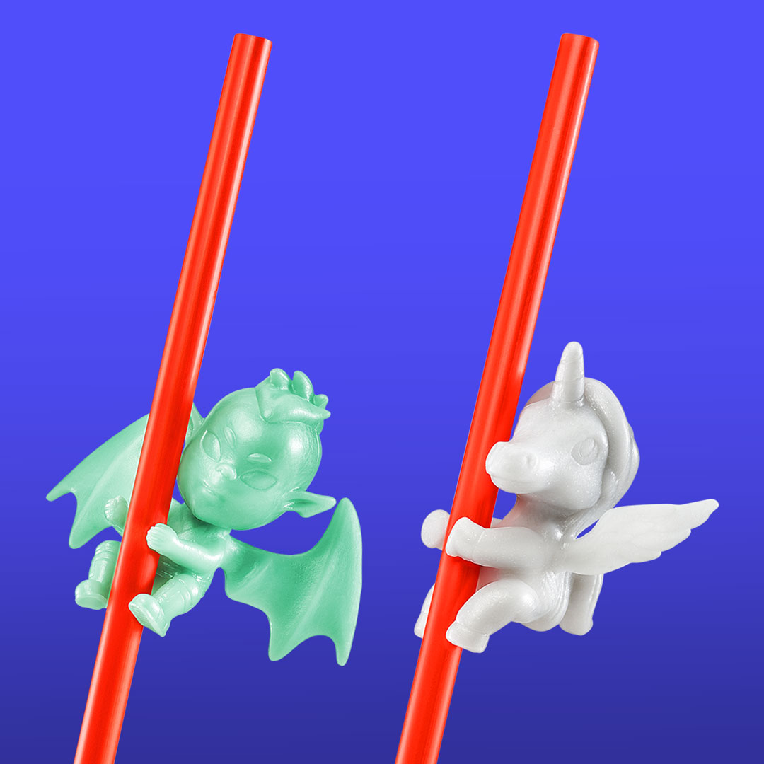 Two small collectible clip-on toys shaped like fantasy creatures attached to red straws. One is a mint green dragon with wings, and the other is a white unicorn with wings and a horn.