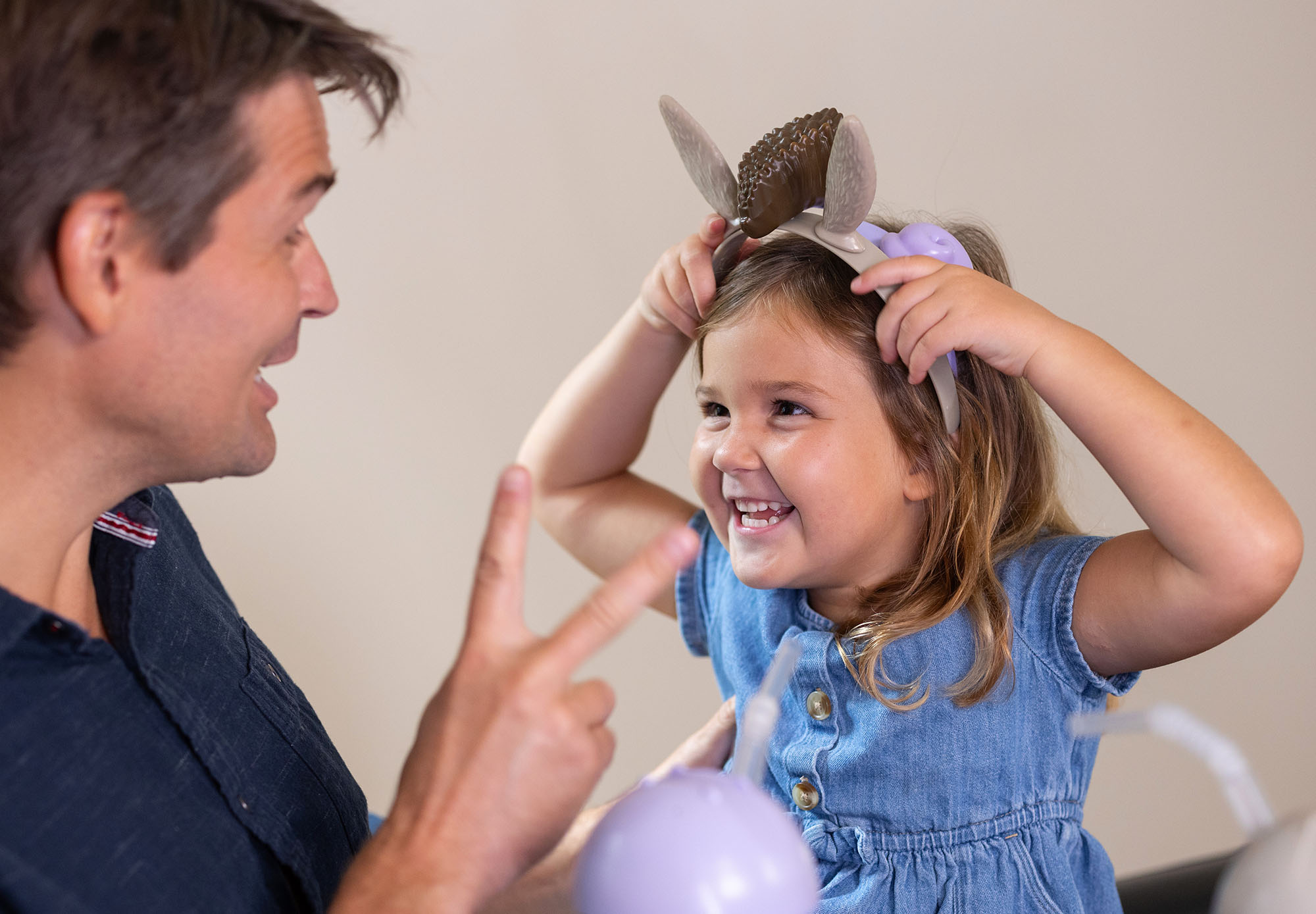 Expertise: Licensing; girl wearing toy headband, showing her father