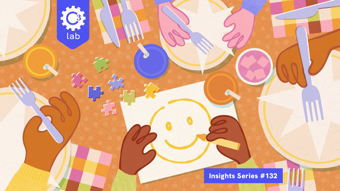 Illustrated overhead view of a restaurant table with multiple hands of different skin tones holding forks, crayons, and puzzle pieces. At the center, a child’s hands draw a large yellow smiley face on white paper with a yellow crayon. Scattered around the table are colorful jigsaw puzzle pieces, orange drinks with straws, and pink bowls. White plates with folded napkins and checkered pink-and-yellow placemats surround the scene. A blue label reads “Insights Series #132” and a C3 Lab logo overlay the scene.