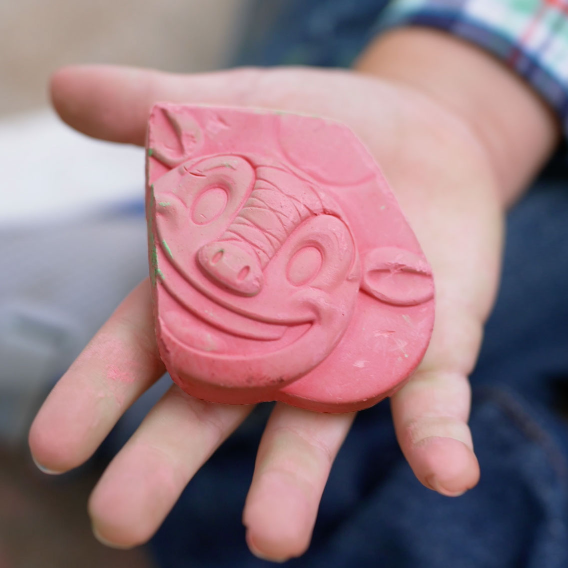 A photo of a Texas Roadhouse Andy the Aardvark molded sidewalk chalk piece being held in a child's hand.